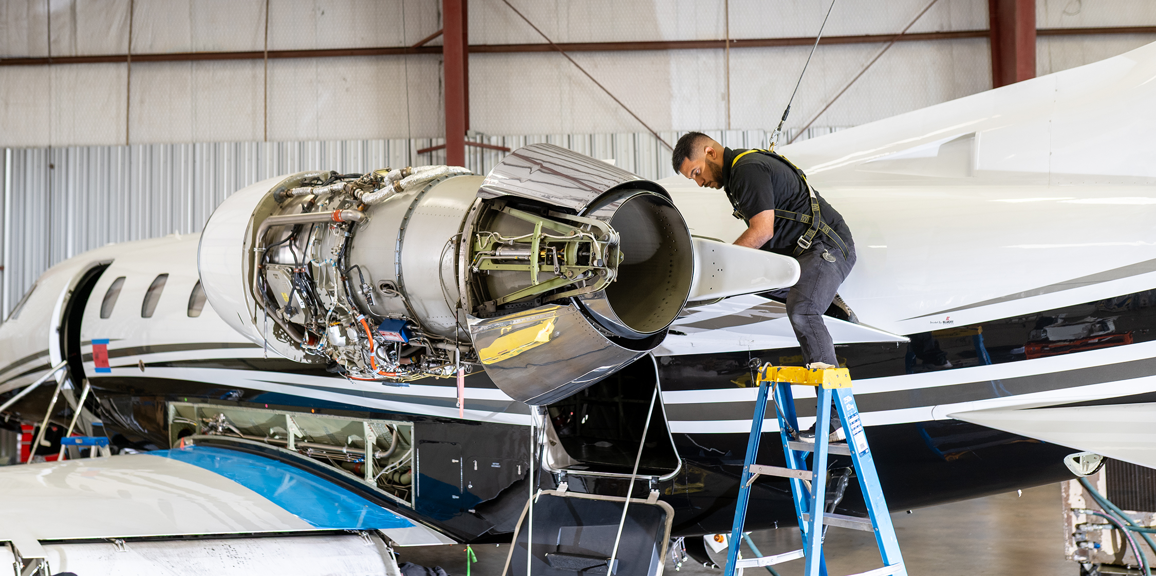 Plane Place Aviation technician on a ladder performing Citation engine work