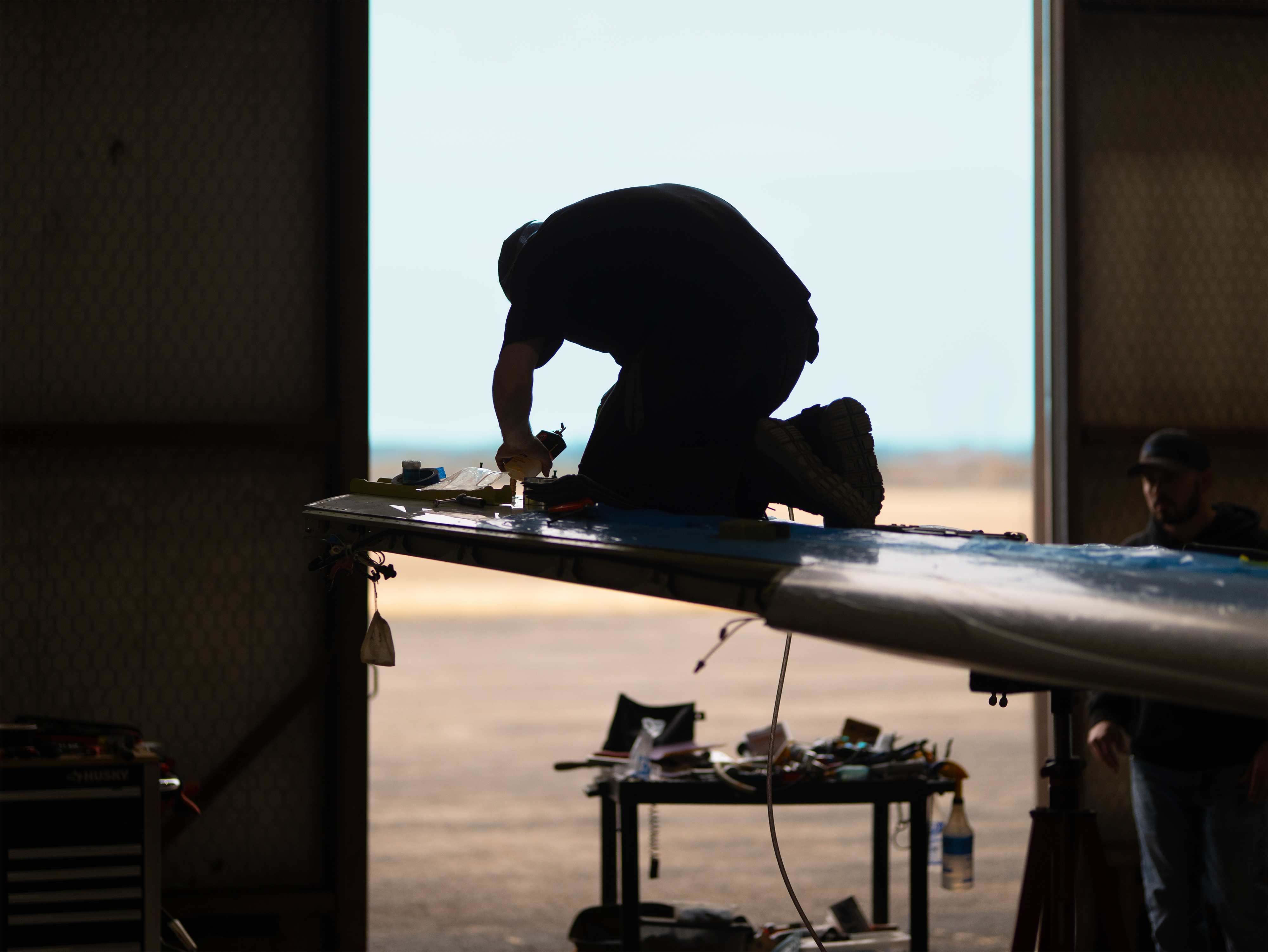 Plane Place Aviation technician silhouette working on wing at sunset